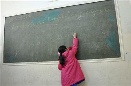 A Kurdish student writes on a board in a classroom in the town of Rumeilan, near the Syrian/Iraqi border, December 10, 2013. Picture taken December 10, 2013. REUTERS/Rodi Said