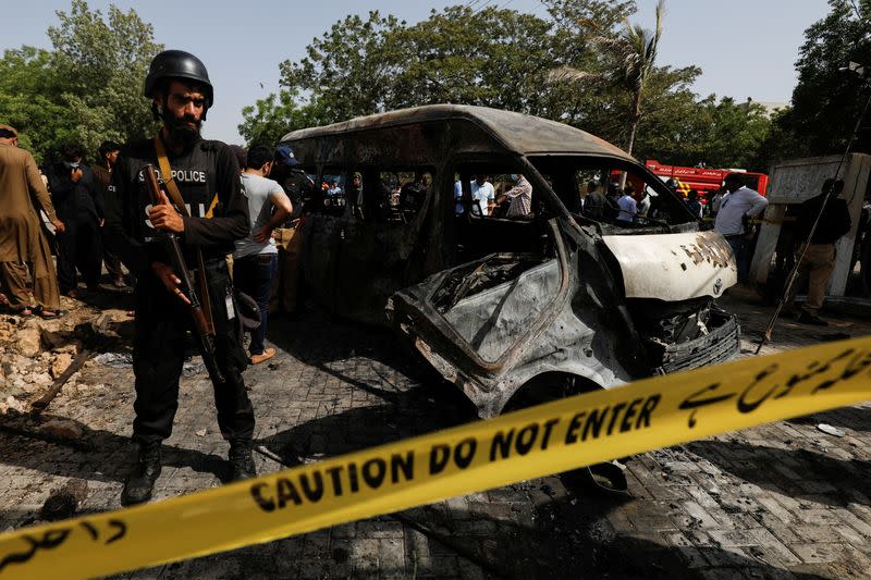 A police officer stands guard near a passenger van, cordoned after a blast at the entrance of the Confucius Institute at University of Karachi