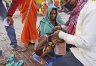 A family get their son head tonsured during Kumbh mela, in Haridwar in the Indian state of Uttarakhand, Monday, April 12, 2021. As states across India are declaring some version of a lockdown to battle rising Covid cases as part of a nationwide second-wave, thousands of pilgrims are gathering on the banks of the river Ganga for the Hindu festival Kumbh Mela. The faithful believe that a dip in the waters of the Ganga will absolve them of their sins and deliver them from the cycle of birth and death. (AP Photo/Karma Sonam)