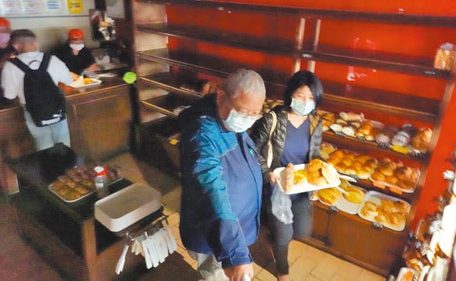 台北市士林捷運站附近商圈3月30日晚間發生停電狀況，麵包店內的顧客靠著手機燈光選購麵包。（姚志平攝）
