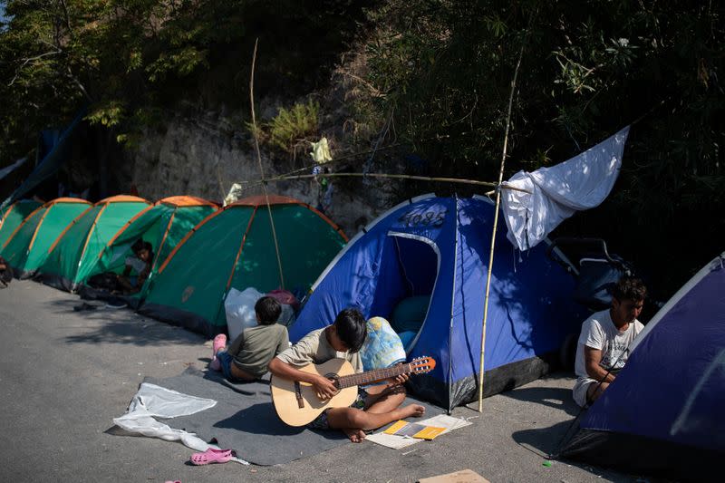 A boy plays the guitar at the area where refugees and migrants from the destroyed Moria camp are sheltered, near a new temporary camp, on the island of Lesbos