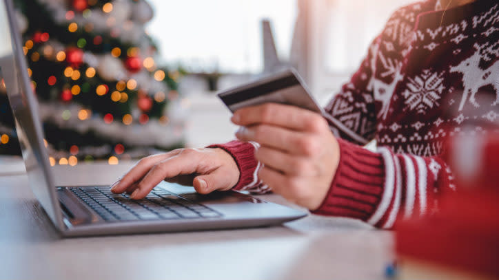 Women wearing red sweater shopping online and using credit card at home office