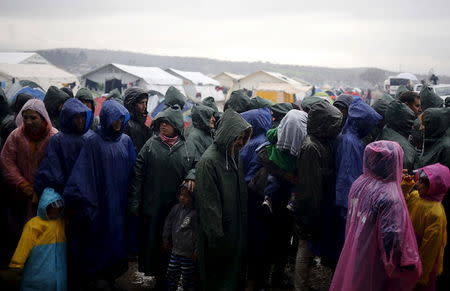 Migrants line up for food during a heavy rainfall at a makeshift camp on the Greek-Macedonian border, near the village of Idomeni, Greece March 9, 2016. REUTERS/Stoyan Nenov