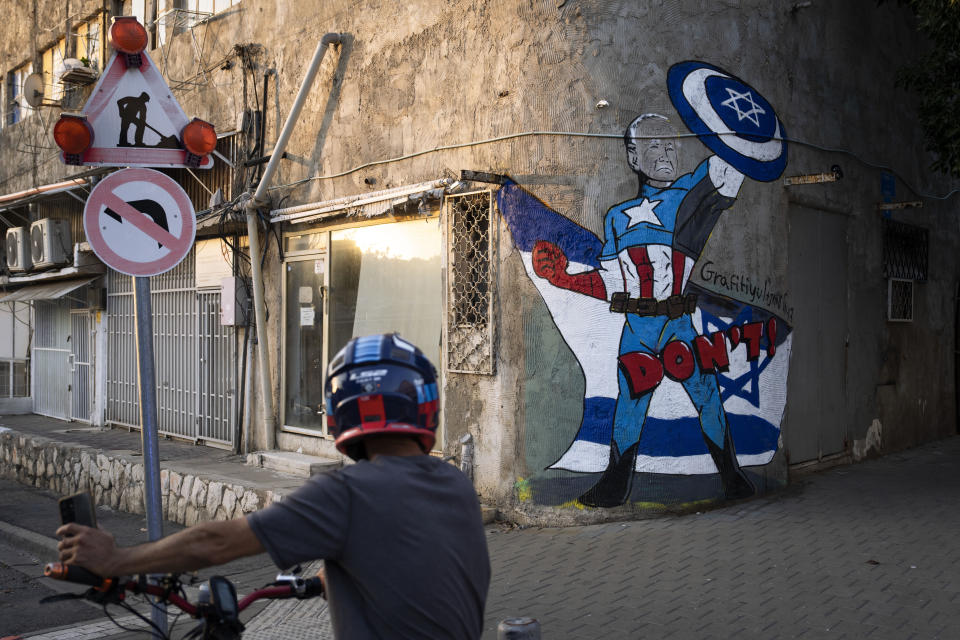 A man rides his bicycle next to a newly painted graffiti of Joe Biden depicts the U.S. president as a superhero defending Israel, Tel Aviv, Israel, Monday, Oct. 30, 2023. Biden's popularity in Israel has soared thanks to his strong support for Israel in its war against Hamas militants. (AP Photo/Oded Balilty)