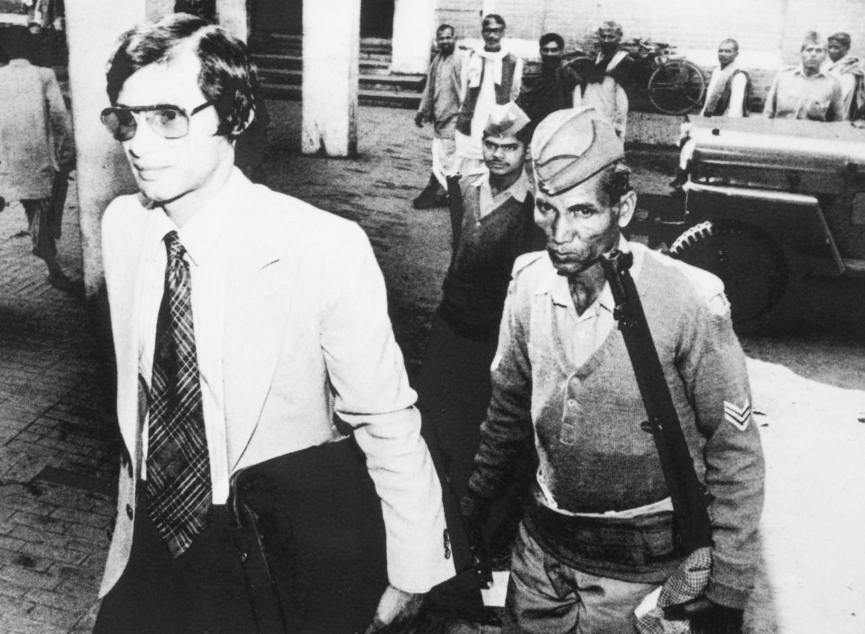 Charles Sobhraj, escorted by a rifle-carrying Indian policeman, enters court on March 3, 1982, in Benares, India. (AP)