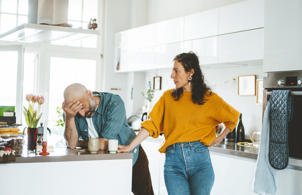 A man and woman in a kitchen, he is holding his head in frustration, she looks on with hands on hips