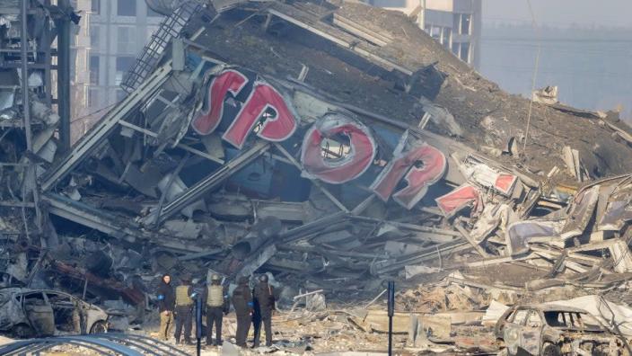 People examine the damage after the shelling of a shopping center in Kyiv, Ukraine