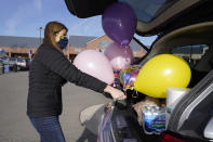 Volunteer Erica Stowe packs groceries and balloons into her vehicle, Thursday, Nov. 19, 2020, in Ann Arbor, Mich. A group of parents has come together to help support University of Michigan students while they are sick or quarantining. The group of mostly moms was started and is organized by Sherry Levine of Rye Brook, New York, who's also a mother of a Michigan student. After she spread the word on parent pages on Facebook, local volunteers stepped up to help fulfill student requests by dropping off groceries or supplies. (AP Photo/Carlos Osorio)