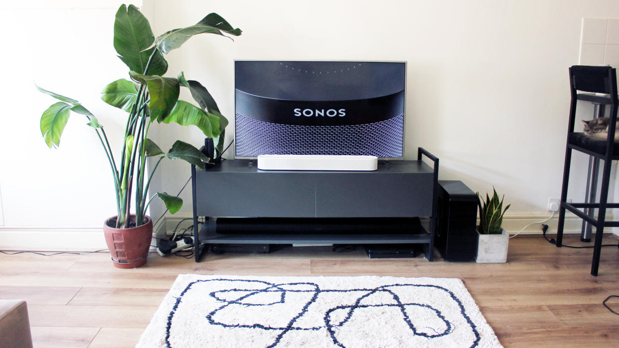  The sonos beam gen 2 soundbar in white pictured beneath a tv on a black cabinet. 