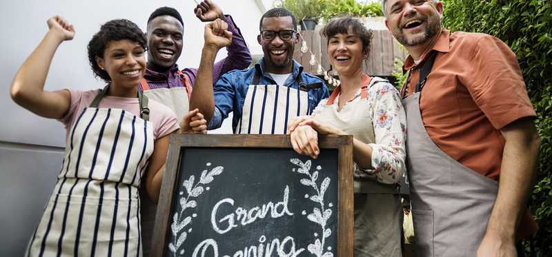 Five people in front of a grand opening sign.