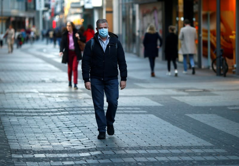 FILE PHOTO: A man wearing a protective mask walks in the main shopping street as shops are closed during the spread of the coronavirus disease (COVID-19) in Cologne