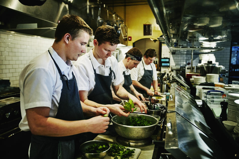 Kitchen staff preparing organic greens for dinner service on the line in restaurant kitchen
