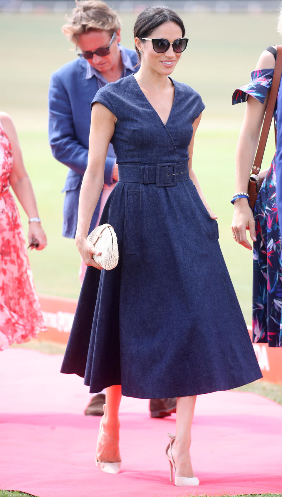 <p>Meghan looked chic in a £2,347 denim Carolina Herrera wrap midi dress with nude Aquazzura heels and a J.Crew rattan bag for the Sentebale Polo 2018 in July 2018 [Photo: Getty] </p>