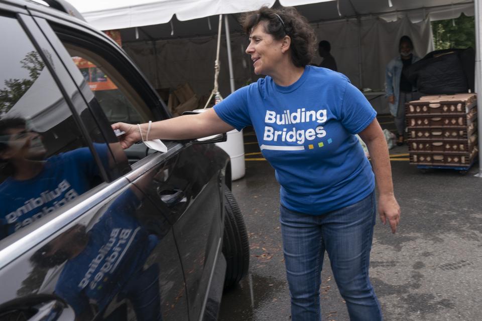 Volunteer Lisa Smith helps distribute bags of produce as well as hot and cold lunches, during a drive through and walk-up food distribution event at the Town Hall Education Arts & Recreation Campus (THEARC), Wednesday, Oct. 6, 2021, in Washington. (AP Photo/Jacquelyn Martin)