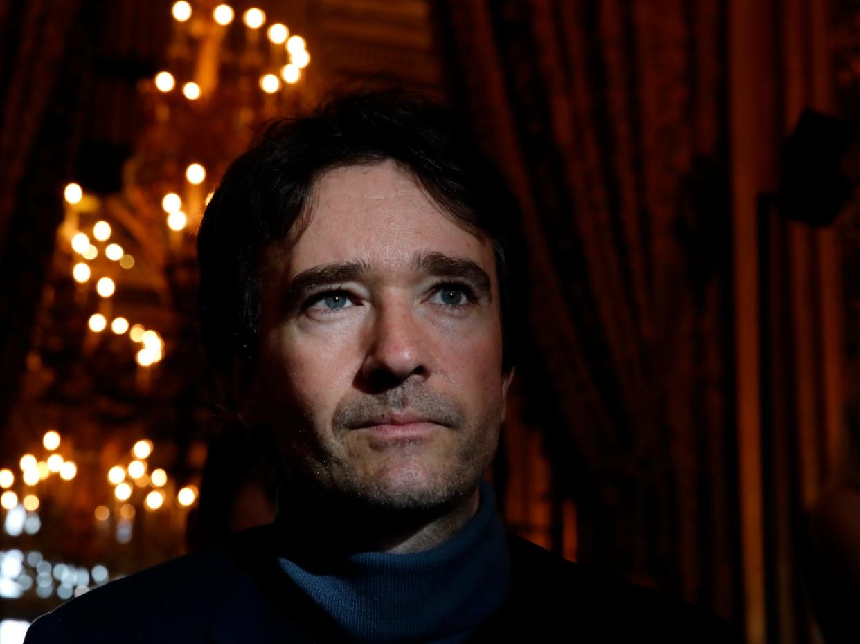 Antoine Arnault backstage at a fashion show looking through curtains