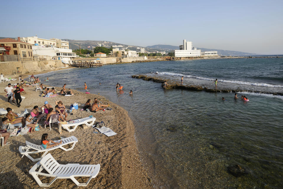 Residents relax on Batroun beach in Batroun village, north of Beirut, Lebanon, Friday, July 2, 2021. With their dollars trapped in the bank, a lack of functioning credit cards and travel restrictions imposed because of the pandemic, many Lebanese who traditionally vacationed over the summer at regional hotspots are also now turning toward domestic tourism. (AP Photo/Hassan Ammar)