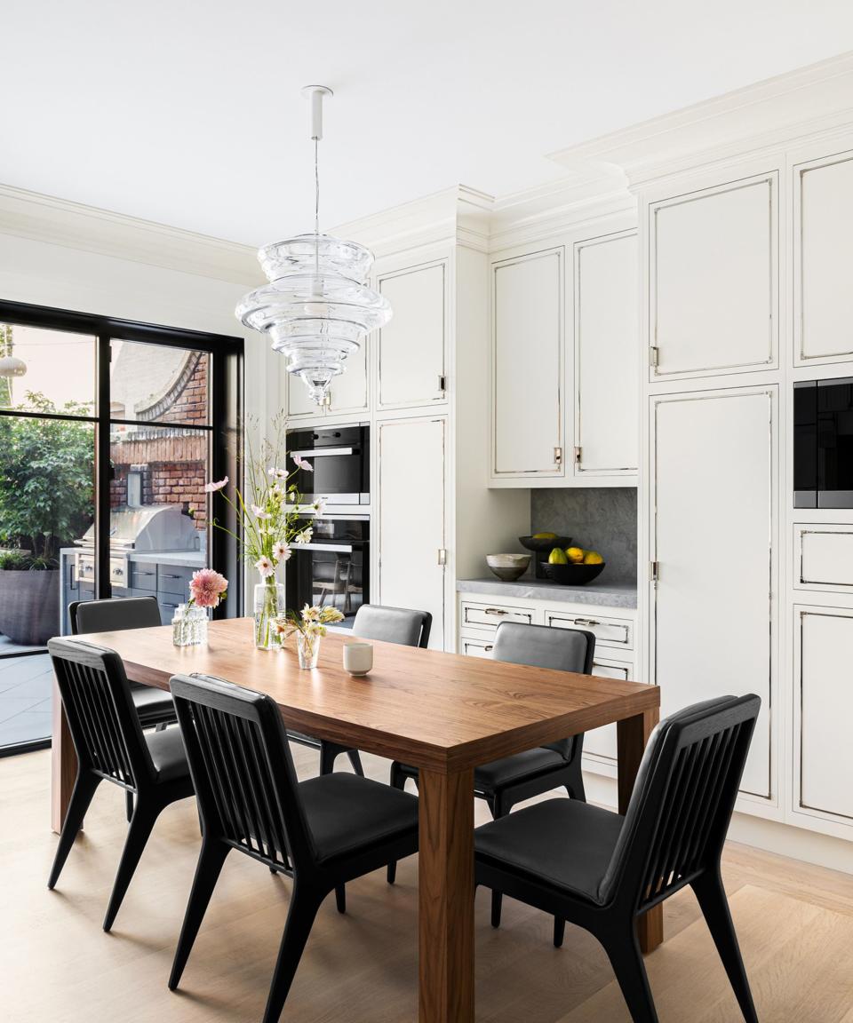 kitchen-diner with white walls and white cabinets with wooden dining table and black chairs