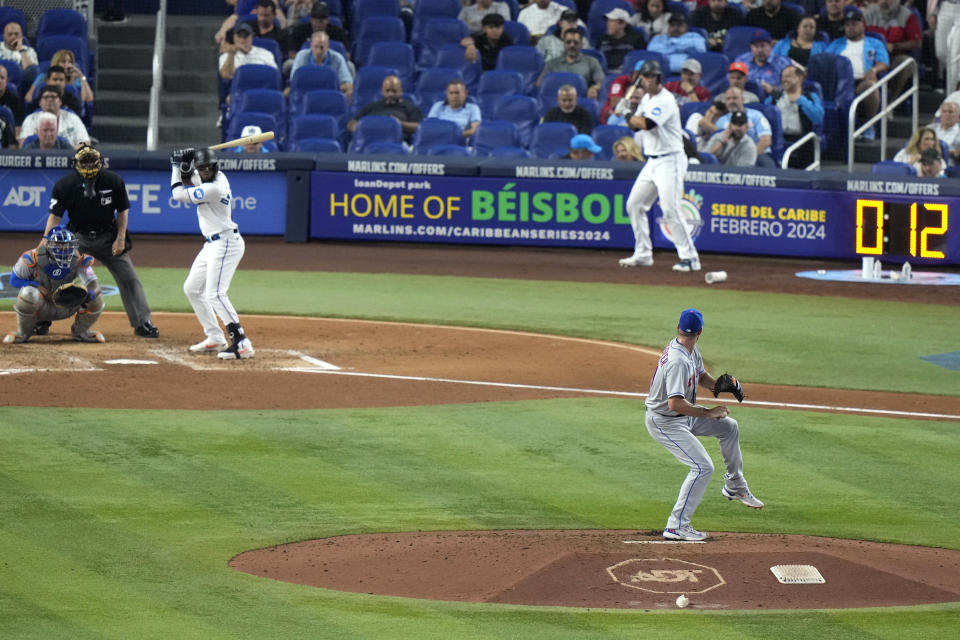 New York Mets starting pitcher Max Scherzer, bottom right, winds up to throw to Miami Marlins' Bryan De La Cruz, third from upper left, as the pitch clock, upper right, runs during the fifth inning of an opening day baseball game, Thursday, March 30, 2023, in Miami. (AP Photo/Lynne Sladky)