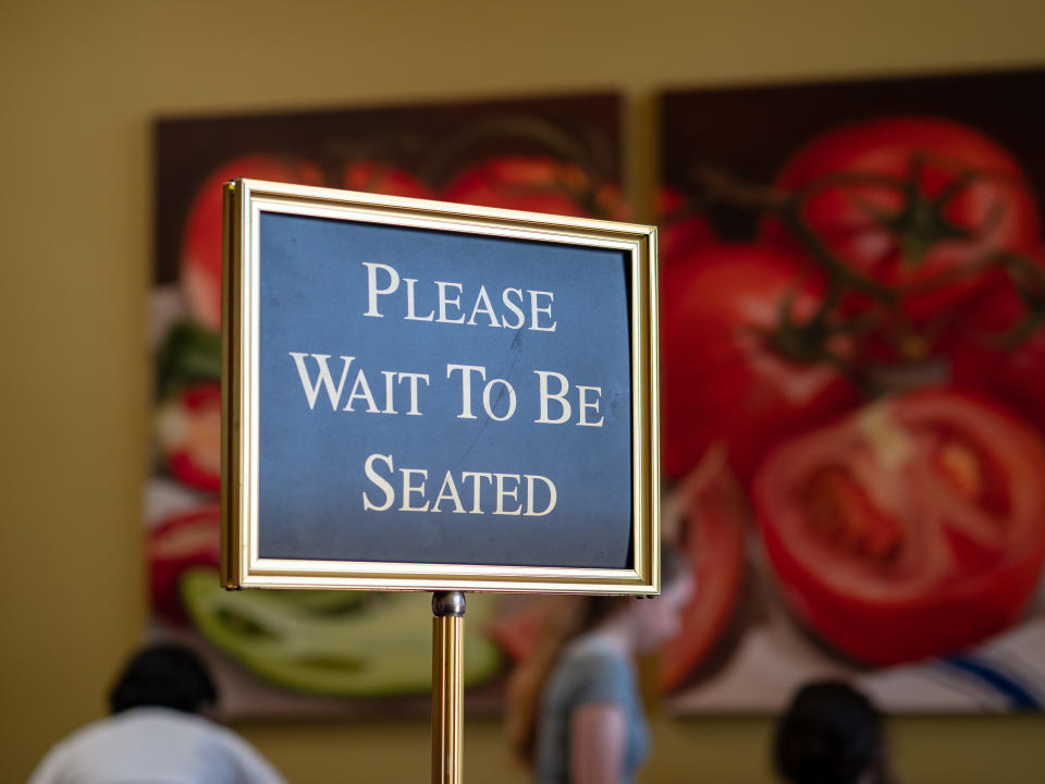 Close-up of "Please wait to be seated" sign