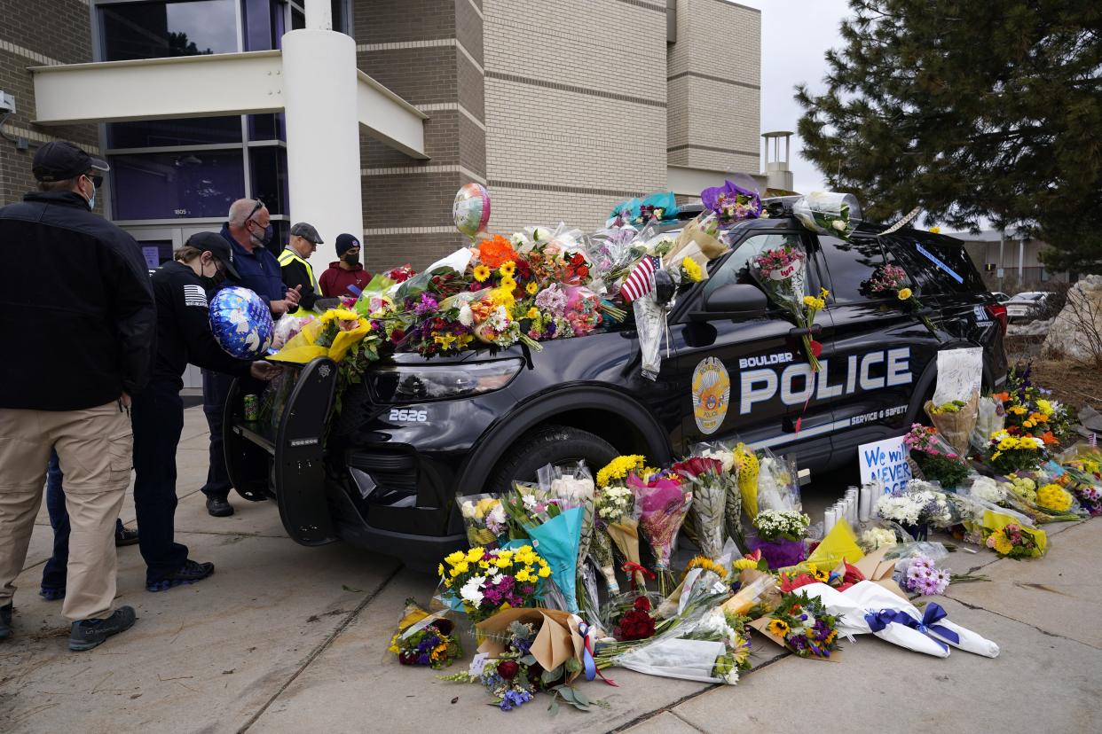 Residents leave bouquets on a police cruiser parked outside the Boulder Police Department after an officer was one of the victims of a mass shooting at a King Soopers grocery store Tuesday, March 23, 2021, in Boulder, Colo. 