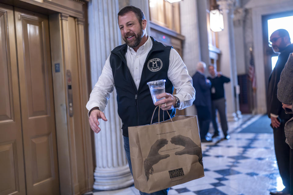 Sen. Markwayne Mullin, R-Okla., arrives with a carryout bag of hamburgers as the Senate prepares a procedural vote on an emergency spending package that would provide military aid to Ukraine and Israel, replenish U.S. weapons systems and provide food, water and other humanitarian aid to civilians in Gaza, at the Capitol in Washington, Sunday, Feb. 11, 2024. (AP Photo/J. Scott Applewhite)