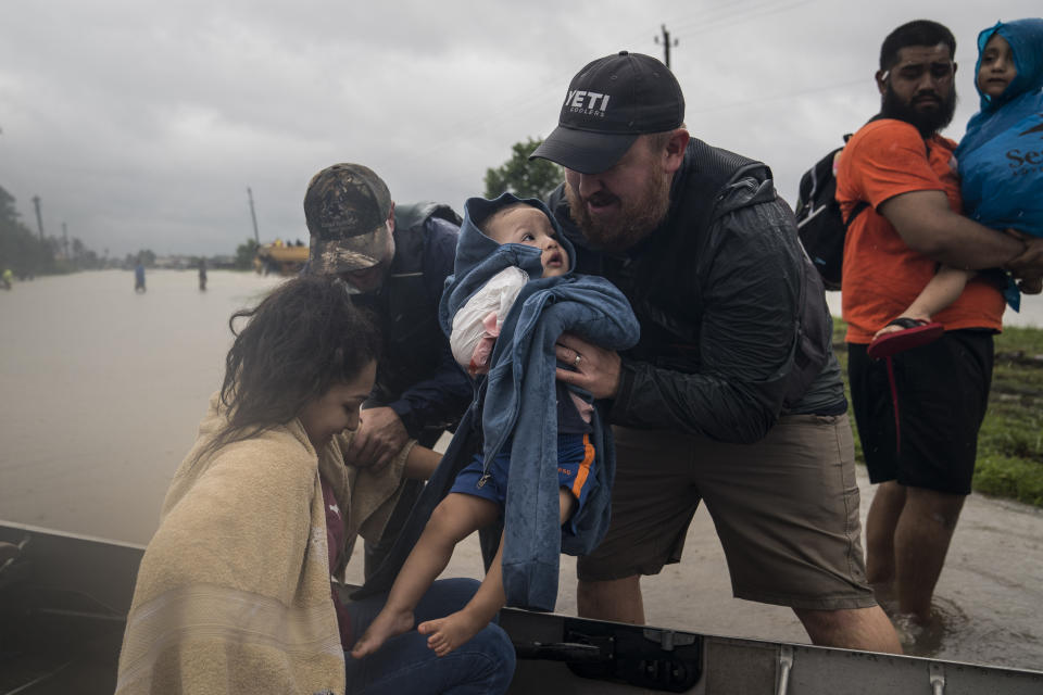 Glenda Montelongeo, Richard Martinez and his two sons are helped out of a boat after being rescued near Tidwell Road and Toll road 8 in Houston.&nbsp;
