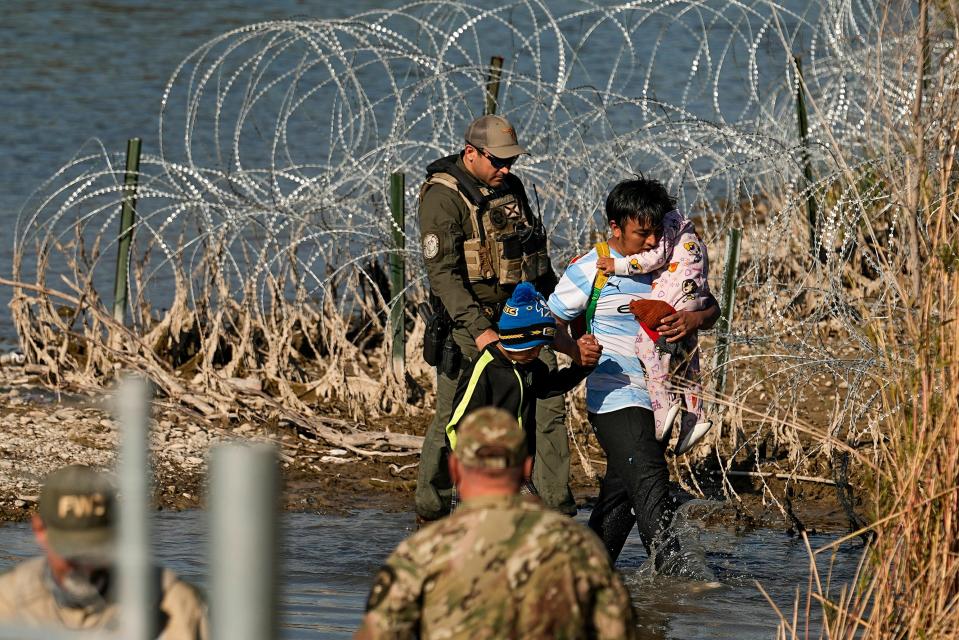 Migrants are taken into custody by officials at the Texas-Mexico border, Wednesday, Jan. 3, 2024, in Eagle Pass, Texas.