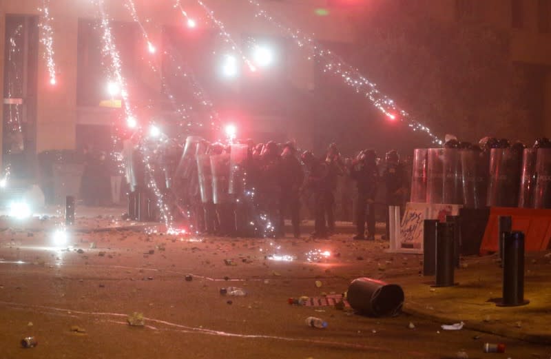 Fireworks are set off in front of police officers standing in position behind riot shields during a protest against a ruling elite accused of steering Lebanon towards economic crisis in Beirut