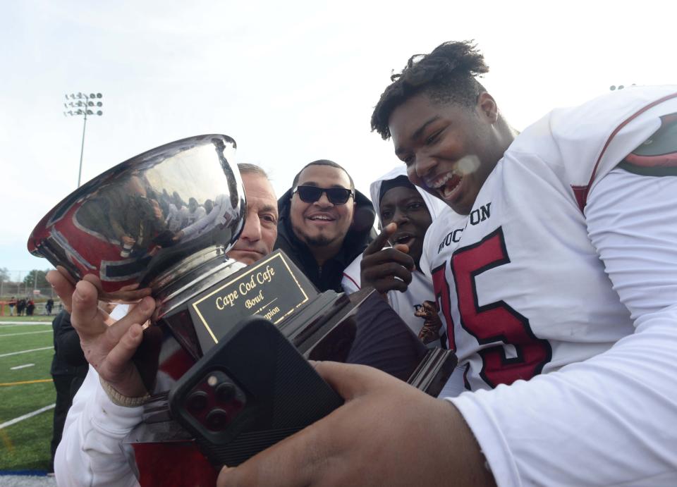 Brockton head football coach Peter Colombo hands the Cape Cod Cafe Bowl to Makhi Boston following the Boxers' 21-20 victory over Bridgewater-Raynham on Thursday, Nov. 25, 2021.