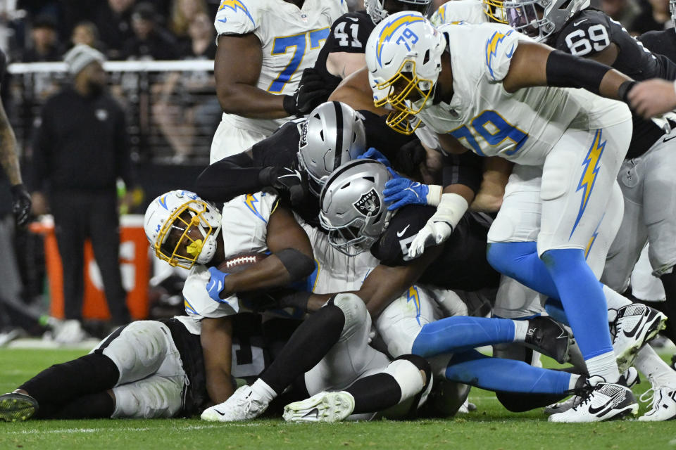 Los Angeles Chargers running back Isaiah Spiller (28) is tackled by the Las Vegas Raiders during the first half of an NFL football game, Thursday, Dec. 14, 2023, in Las Vegas. (AP Photo/David Becker)