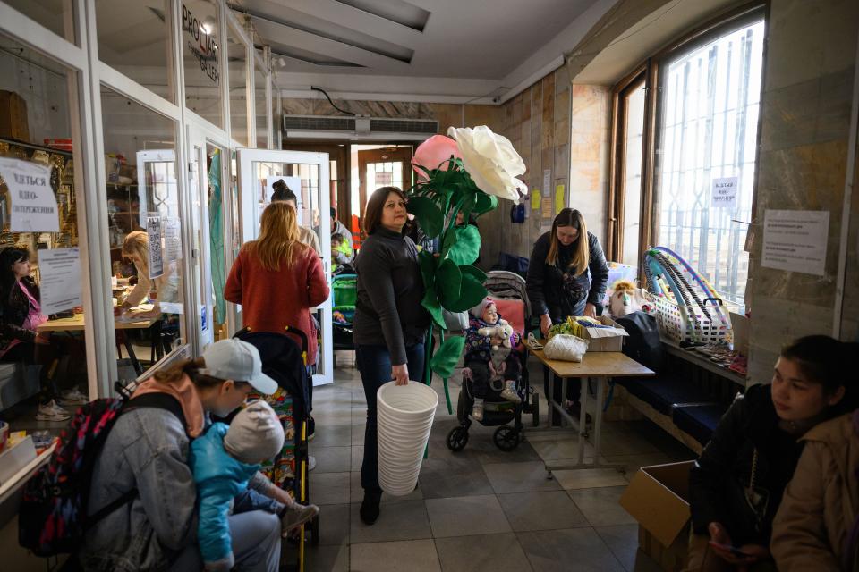 A woman carrying a large artificial flower walks into a central aid processing and distribution center on May 02, 2022, in Lviv, Ukraine. Lviv has served as a stopover and shelter for the millions of Ukrainians fleeing the Russian invasion, either to the safety of nearby countries or the relative security of western Ukraine.