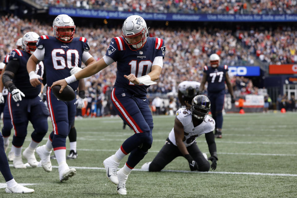 New England Patriots quarterback Mac Jones (10) celebrates in the end zone after running for a touchdown as Baltimore Ravens linebacker Josh Bynes, center right, looks on in the first half of an NFL football game against the Baltimore Ravens, Sunday, Sept. 25, 2022, in Foxborough, Mass. (AP Photo/Paul Connors)