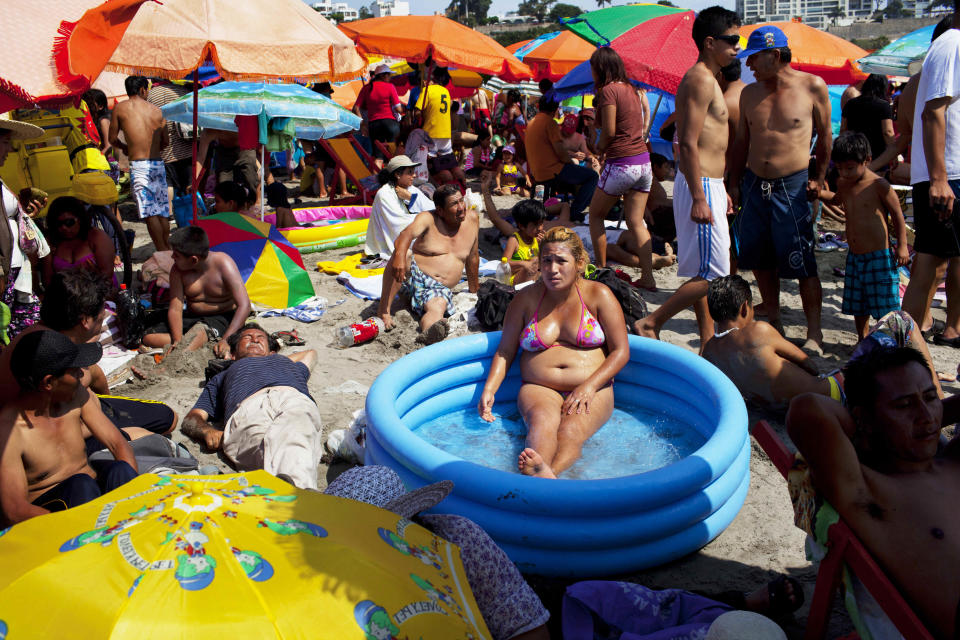 In this Jan. 27, 2013 photo, a woman cools off in a wading pool on Agua Dulce beach in Lima, Peru. While Lima's elite spends its summer weekends in gate beach enclaves south of the Peruvian capital, the working class jams by the thousands on a single municipal beach of grayish-brown sands and gentle waves. On some weekends during the Southern Hemisphere summer, which runs from December until March, as many as 40,000 people a day visit the half-mile-long (kilometer-long) strip of Agua Dulce. (AP Photo/Rodrigo Abd)