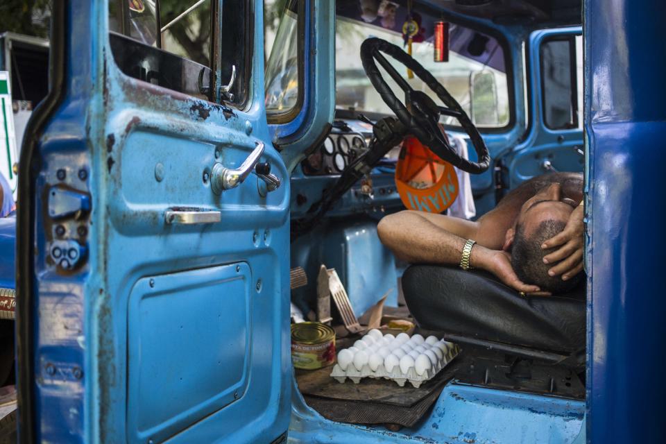 FILE - In this July 21, 2018 file photo, a driver takes a nap in the cabin of his truck at an outdoor food market in Havana, Cuba. (AP Photo/Desmond Boylan, File)