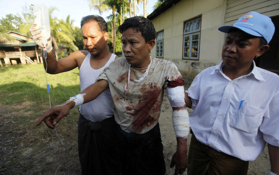 In this Tuesday, Oct. 1, 2013 photo, an injured Rakhine Man, centre, is helped to go to hospital in Thandwe, Rakhine State, western Myanmar. Buddhist mobs killed a 94-year-old Muslim woman and torched more than 70 homes on Tuesday as sectarian violence again gripped Myanmar's Rakhine state despite a visit by President Thein Sein, officials and residents said. (AP Photo/Khin Maung Win)