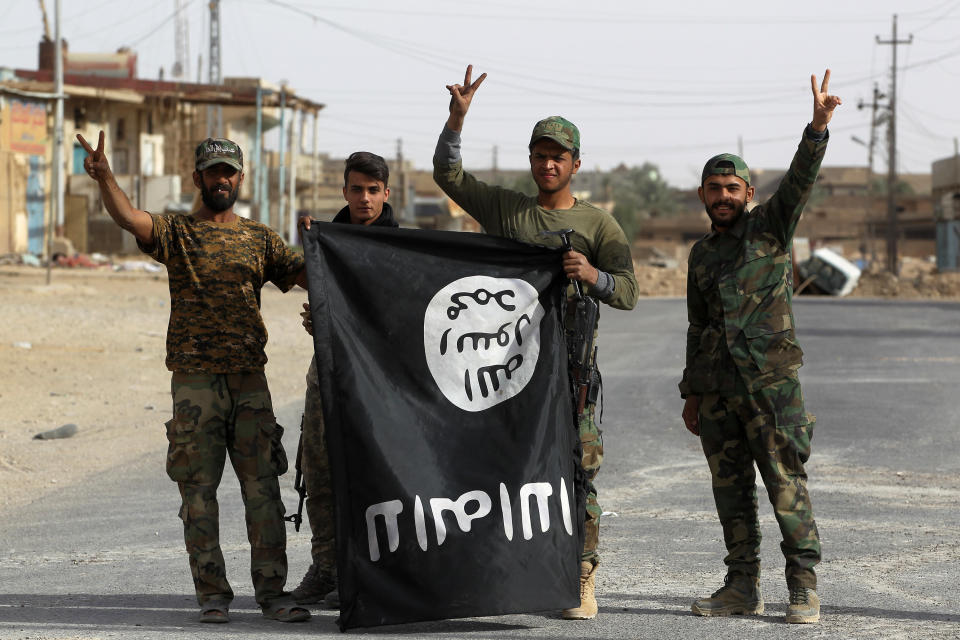 Iraqi members of the Hashed al-Shaabi (Popular Mobilisation units) carry an upsidedown Islamic State (IS) group flag in the city of al-Qaim, in Iraq's western Anbar province near the Syrian border as they fight against remnant pockets of Islamic State group jihadists on November 3, 2017.  / AFP PHOTO / AHMAD AL-RUBAYE        (Photo credit should read AHMAD AL-RUBAYE/AFP/Getty Images)