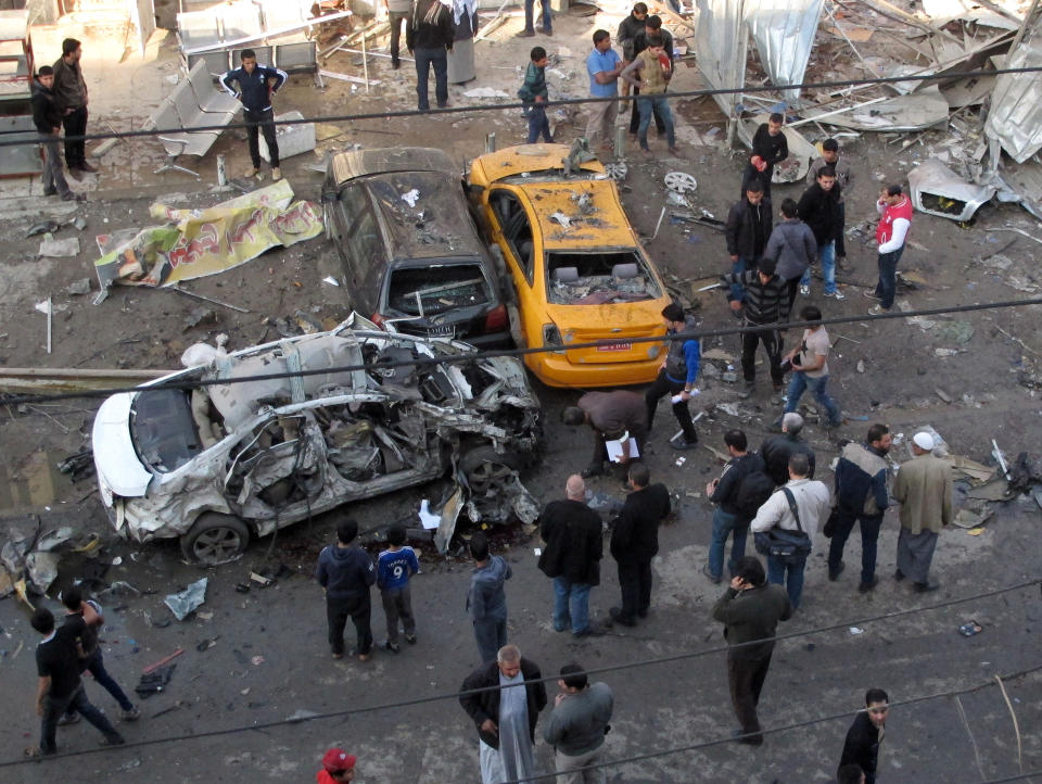 Civilians gather at the site of a car bomb attack at an outdoor market in Baghdad al-Jadidah district, Iraq, Monday, Jan. 20, 2014. A series of bombings in central Iraq killed dozens of people on Monday, as a government official claimed that al-Qaida-linked fighters have dug in to a city they seized last month and possess enough heavy weapons to storm into the country's capital. (AP Photo/Khalid Mohammed)