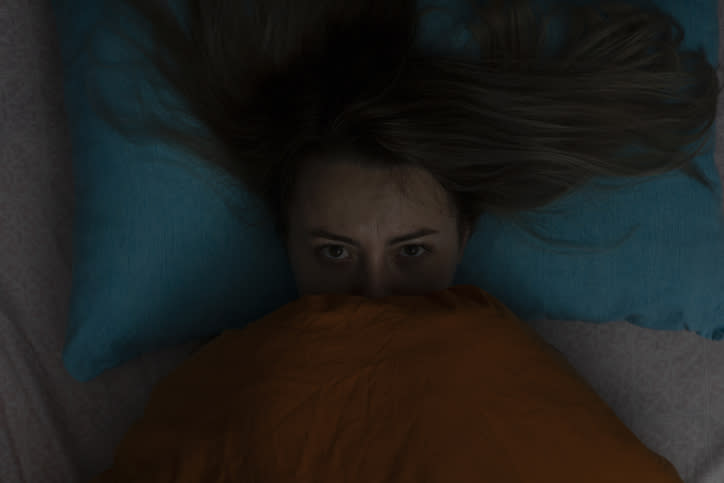 A woman in bed with the blankets pulled up to her face