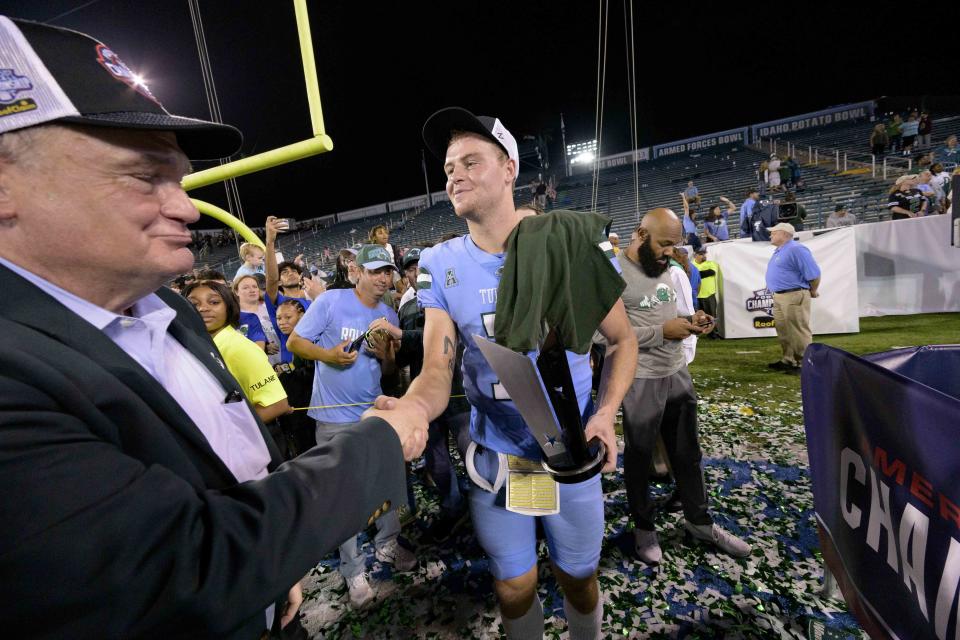 Tulane University President Michael A. Fitts shakes hands with Tulane quarterback Michael Pratt after their team's victory against Central Florida at the end of the American Athletic Conference championship NCAA college football game in New Orleans, Saturday, Dec. 3, 2022. (AP Photo/Matthew Hinton)