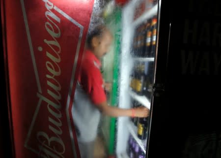 A worker arranges Budweiser beer bottles in a cooler at a liquor shop in Kolkata