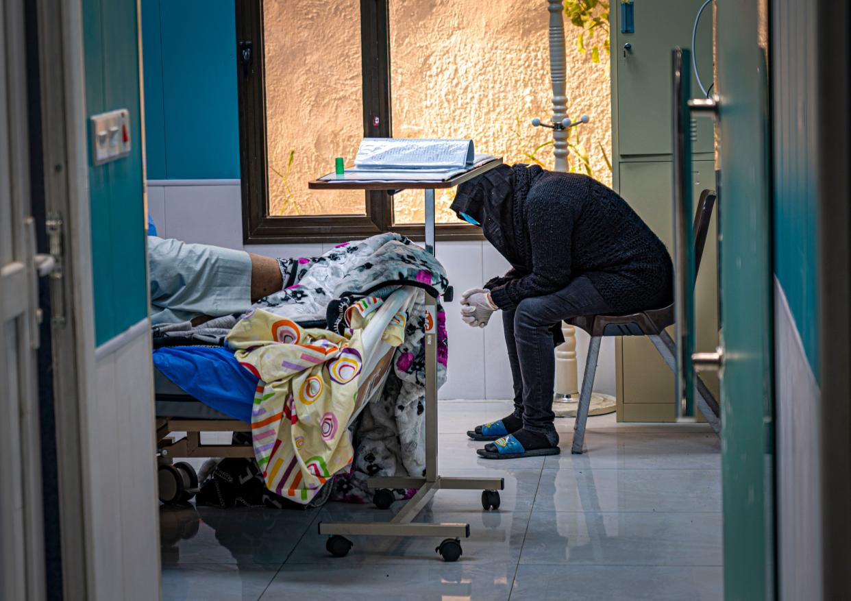 <p>A woman anxiously waits for news on her critically ill husband’s condition</p> (Bel Trew)