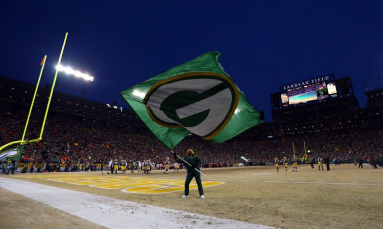 A man waving a Green Bay Packers flag at Lambeau Field.