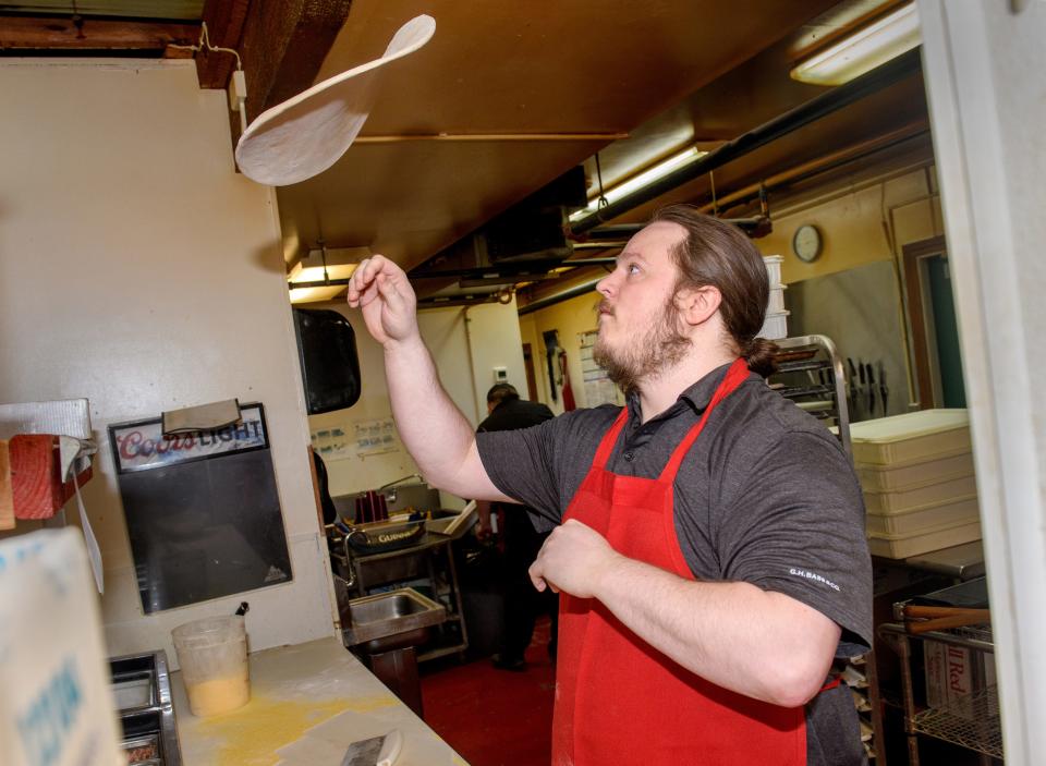 Ryan Moore of Knuckles Pizza tosses a pie into the air in the kitchen at the popular Quad Cities-style pizzeria and sports bar in Dunlap.