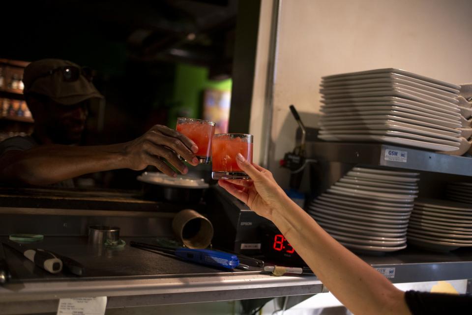 Dwayne Allen and chef Danielle Leoni "cheers" one other with rum punch during The Breadfruit and Rum Bar's final service on March 19, 2020, in Phoenix.