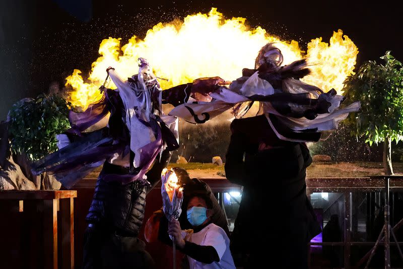 Two Pili puppet characters battle each other while a staff member lights fires as a special effect during a demonstration at their filming studio in Yunlin