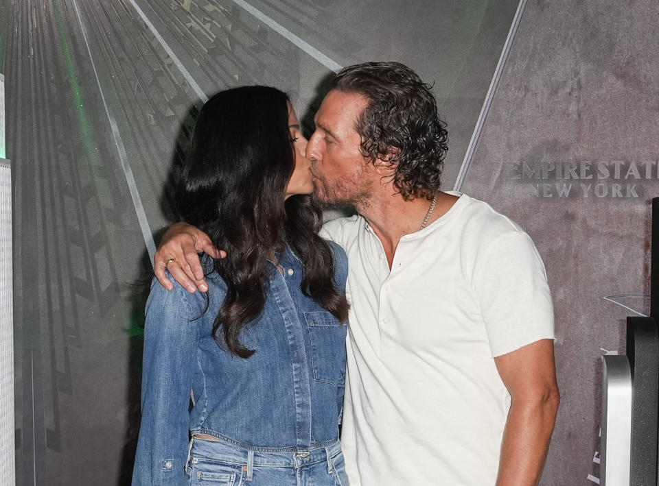 Matthew McConaughey, wearing a white T-shirt, kisses his wife Camila Alves, wearing a denim shirt and jeans