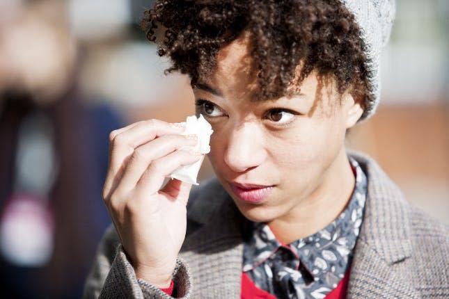 A crying woman blots her eyes with a tissue