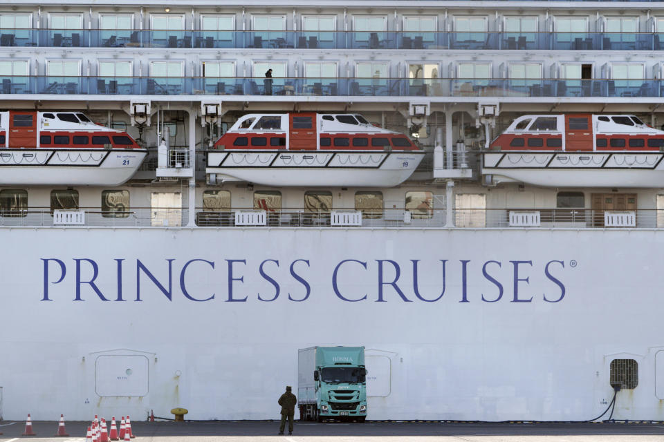 A passenger stands on the balcony of the quarantined cruise ship Diamond Princess anchored at the Yokohama Port in Yokohama, near Tokyo Sunday, Feb. 9, 2020. Japan on Saturday reported three more cases of the coronavirus aboard the Diamond Princess for a total of 64. There are 3,700 passengers and crew on the Diamond Princess who must remain on board for 14 days. (AP Photo/Eugene Hoshiko)