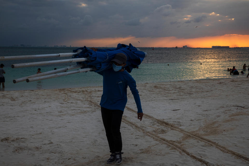 A worker collects beach umbrellas at the end of the day at Isla Mujeres, Quintana Roo, on Dec. 2.<span class="copyright">Claudia Guadarrama—Magnum Foundation for TIME</span>