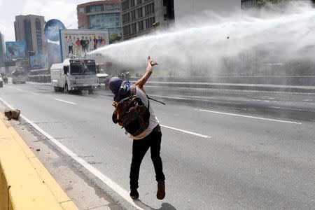 A demonstrator throws a stone toward a riot security forces water cannon vehicle during a rally against Venezuela's President Nicolas Maduro in Caracas, Venezuela, May 26, 2017. REUTERS/Marco Bello
